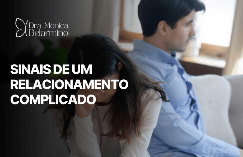 Casal em silêncio e afastado no sofá, cena que ilustra falta de diálogo e insegurança, entre os sinais de um relacionamento complicado.